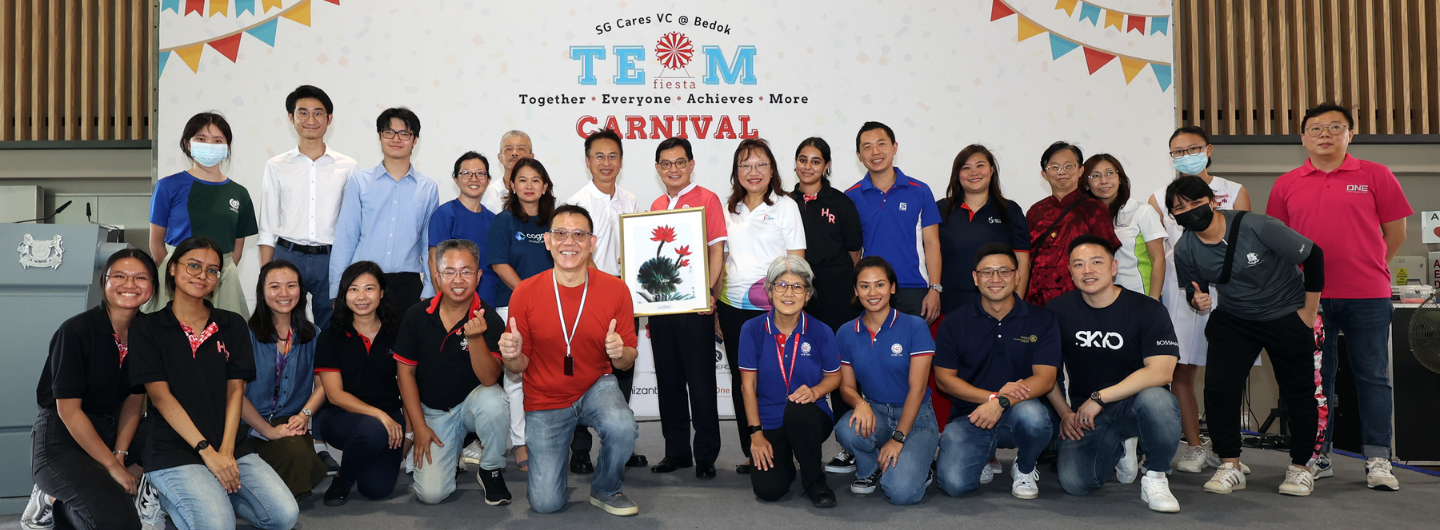 Group of people pose in front of a "TEAM fiesta CARNIVAL" banner.